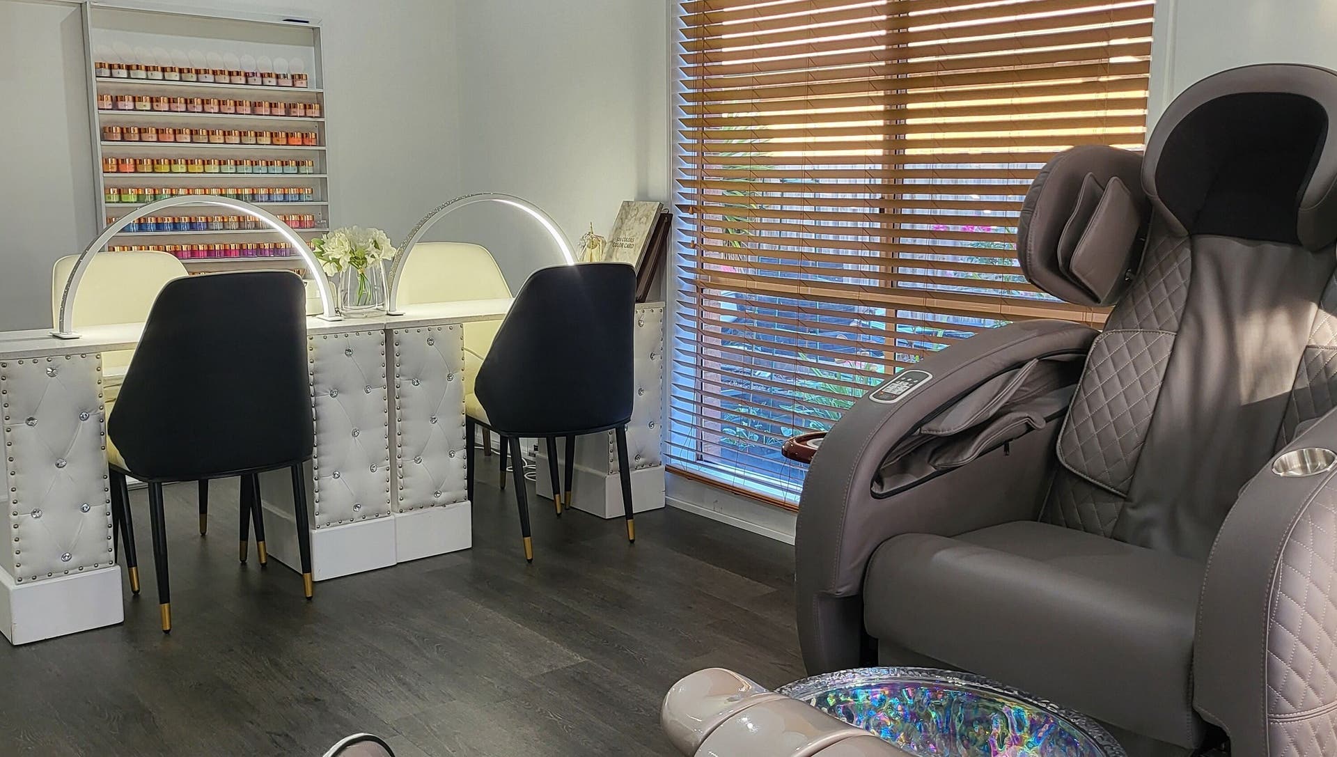 Inside the studio: white tufted manicure desks, grey quilted pedicure chairs and a wall of polish